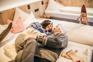 Pärchen im Bett eines Zimmers der Pension