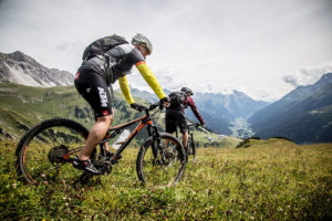 Zwei Mountainbiker auf einer Alm-Wiese